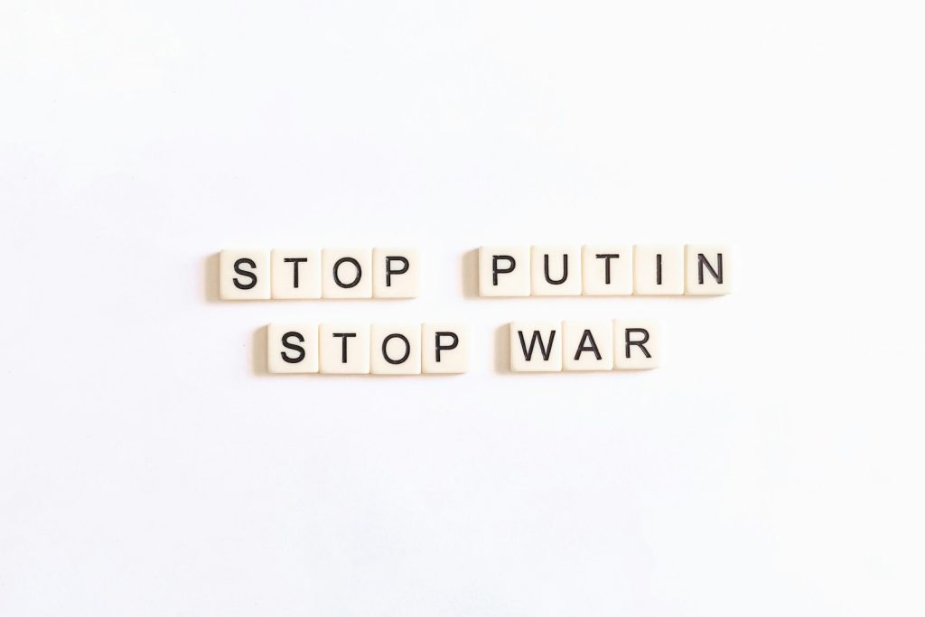 three scrabble tiles spelling stop, putin, and war